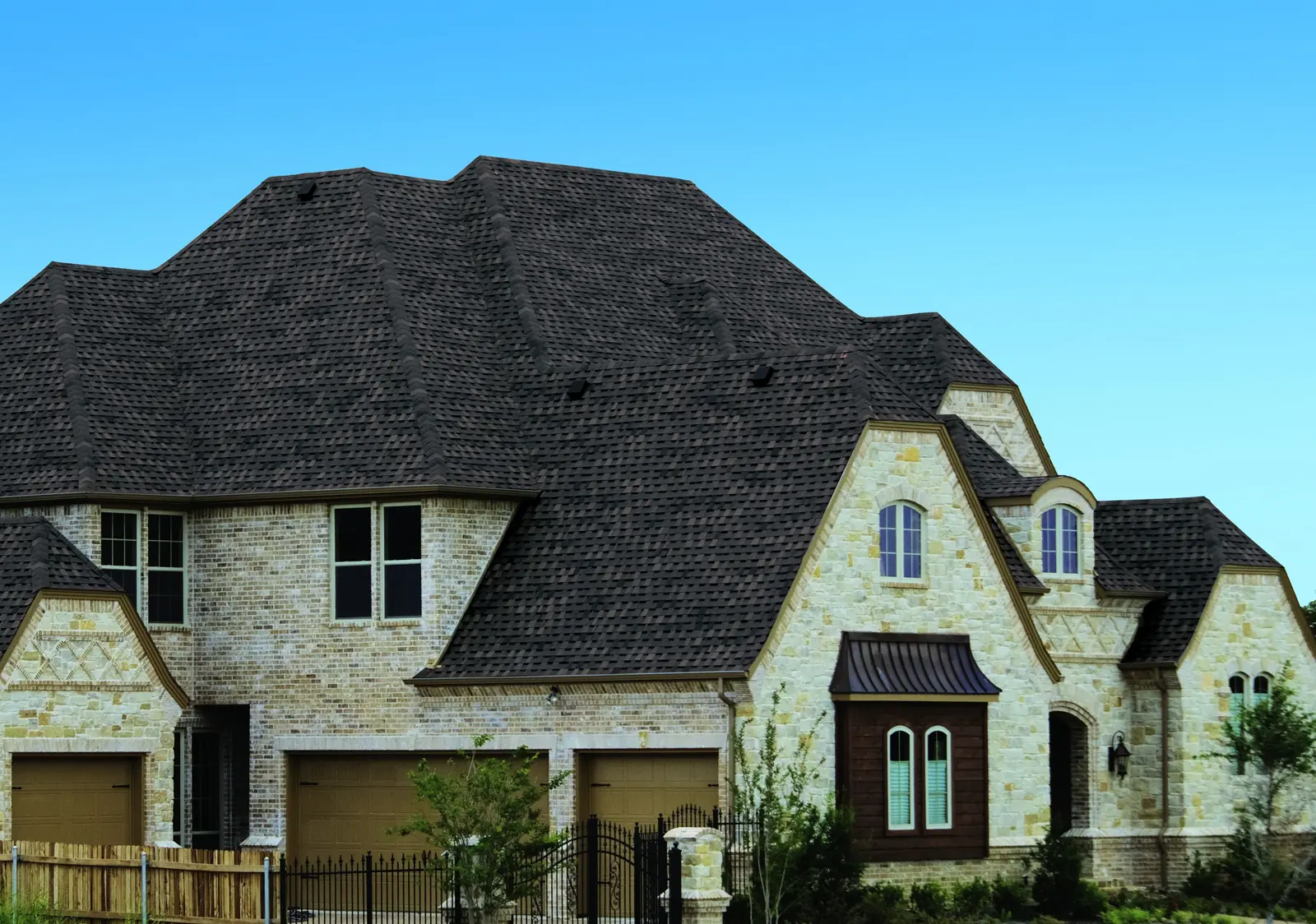 Brick and limestone house with a steep multi-hip Atlas StormMaster Shake roof in Midnight Lake