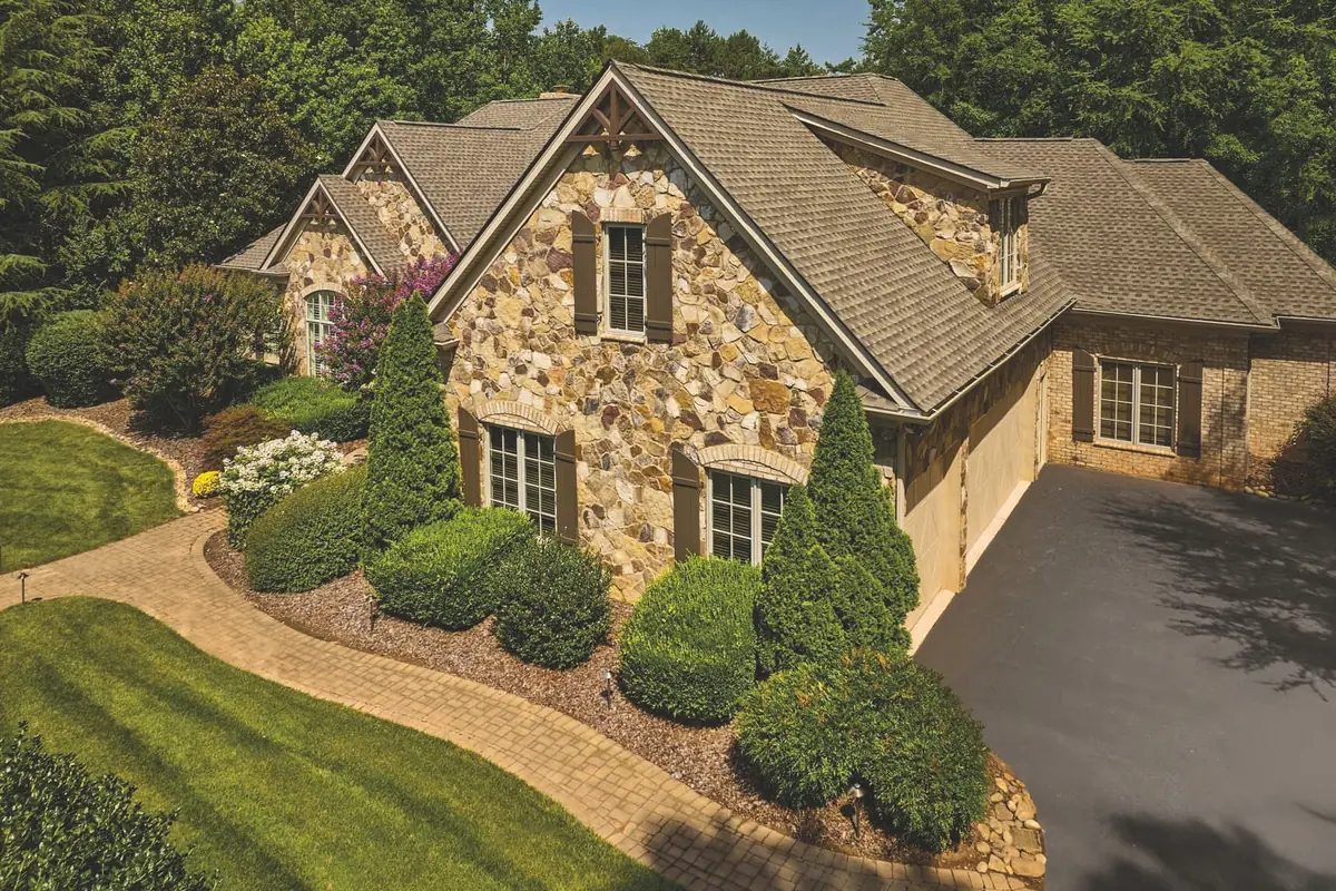 Stone and brick home with a GAF Timberline ArmorShield II roof in Weathered Wood