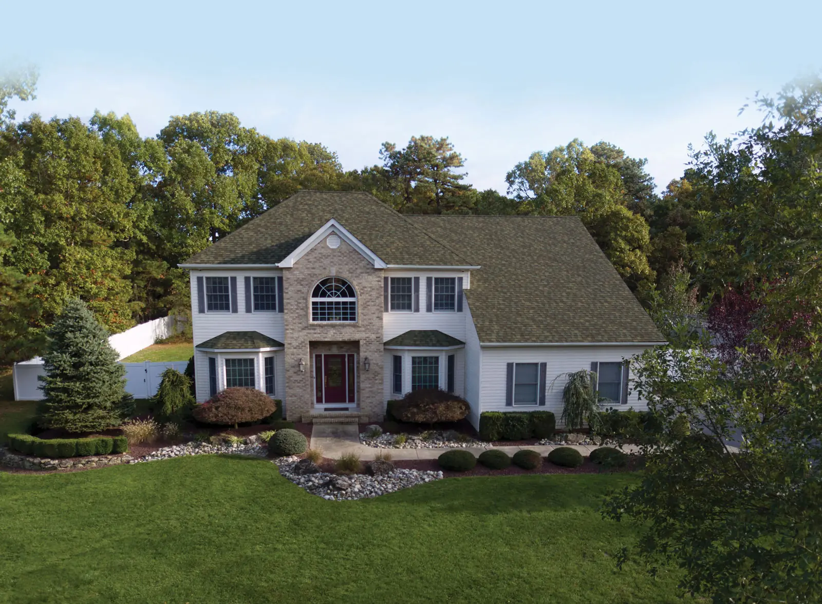 White two-story colonial with a tan brick entry and an IKO Nordic roof
