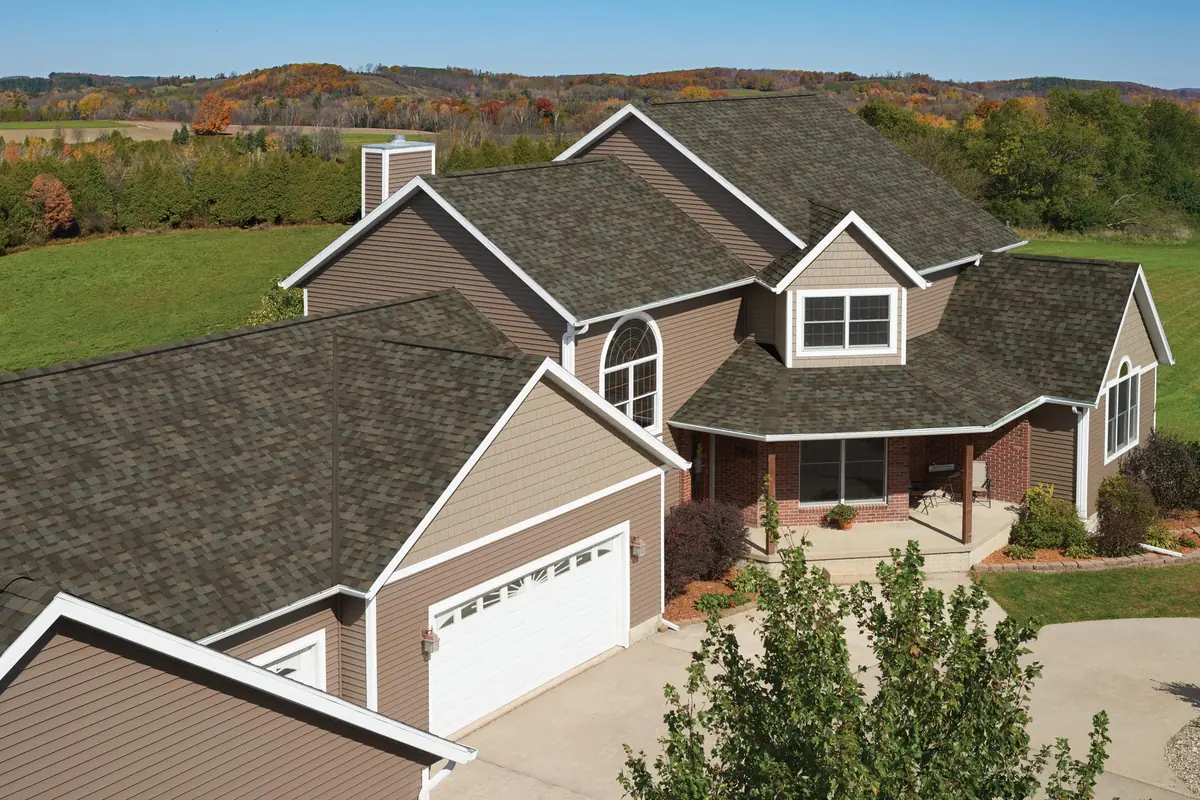 Two-story home with brown siding and an IKO Nordic roof, with farm fields behind
