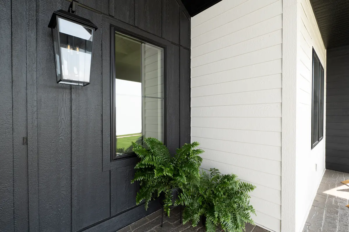 Front porch where black LP SmartSide cedar-texture panel siding and window trim meet white lap siding