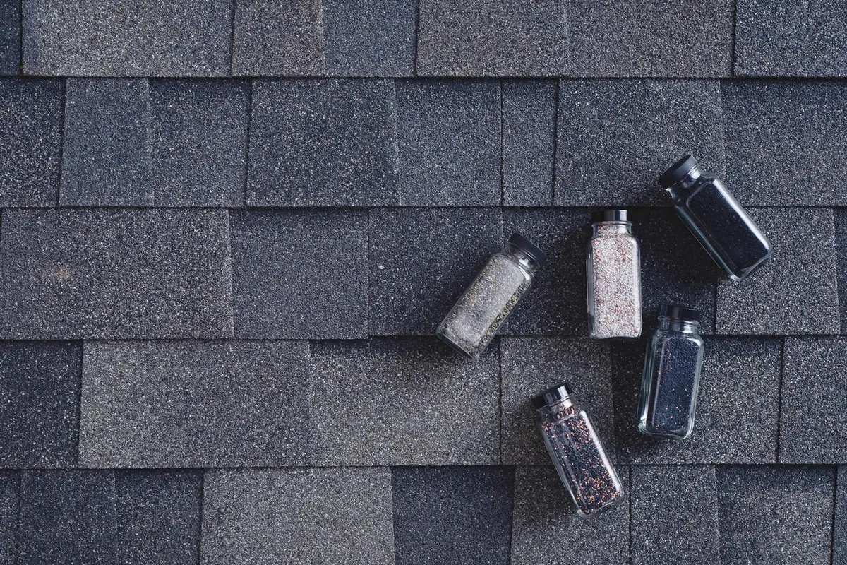Close-up of a Malarkey Storm Grey shingle surface with small jars of roofing granules
