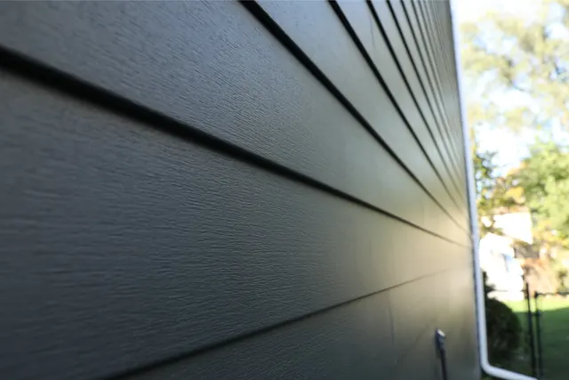 Close view along a wall of dark Mastic EverPlank vinyl lap siding