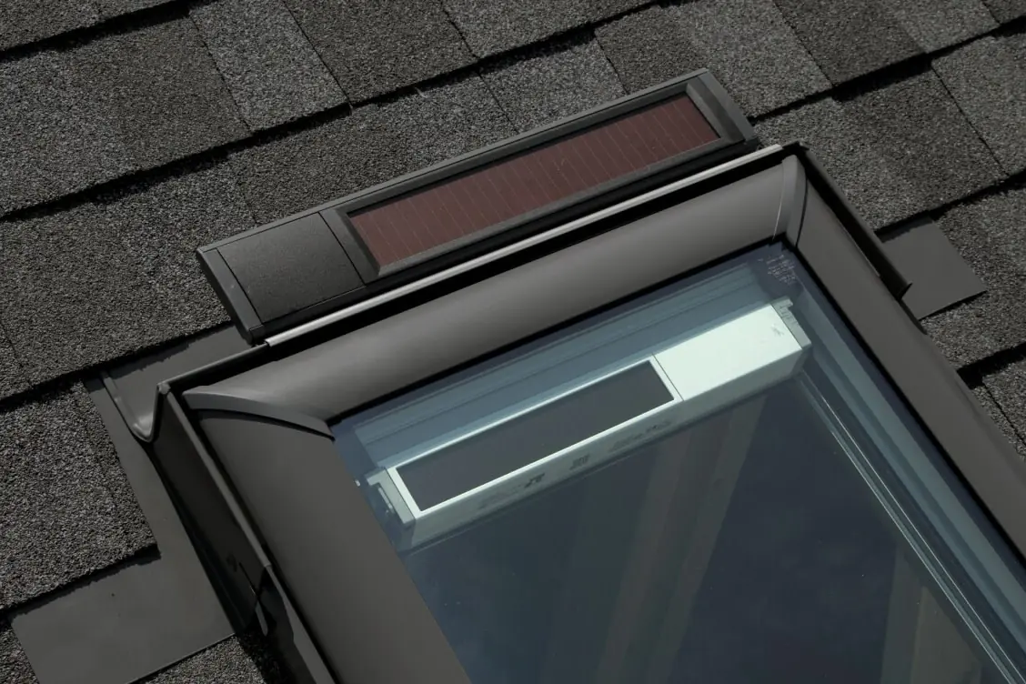 Corner of a VELUX skylight on a shingle roof, with the step flashing woven into the shingles