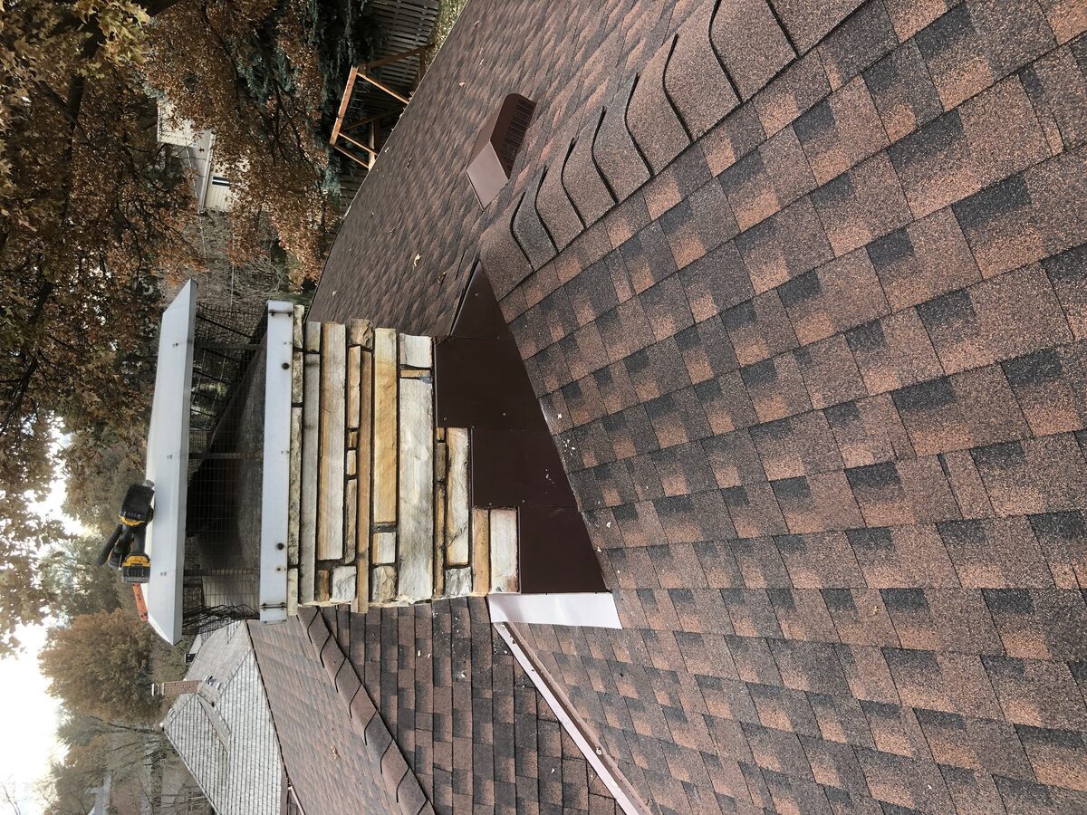 Completed roof with custom chimney flashing on stone veneer chimney