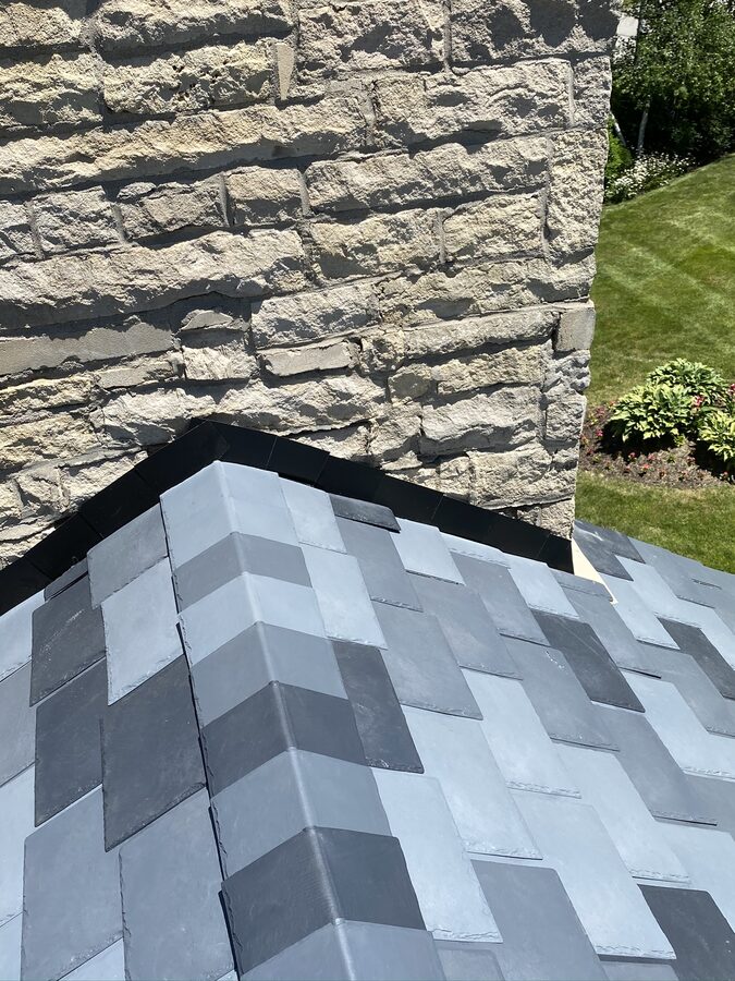 Close-up of DaVinci synthetic slate roof meeting stone chimney