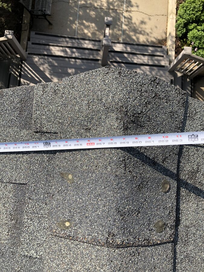 Measuring hail damage on ridge cap shingles during roof assessment