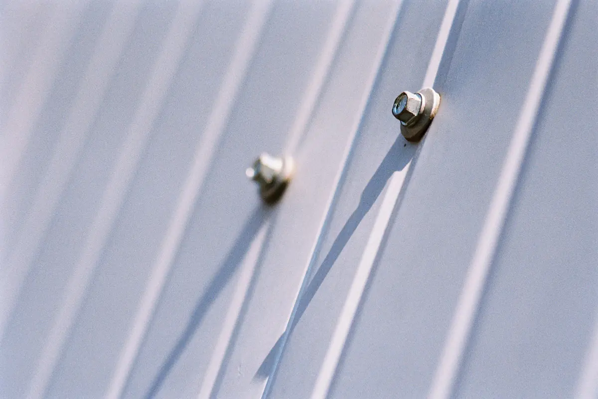 Hex-head screws with sealing washers driven through the face of a ribbed steel panel