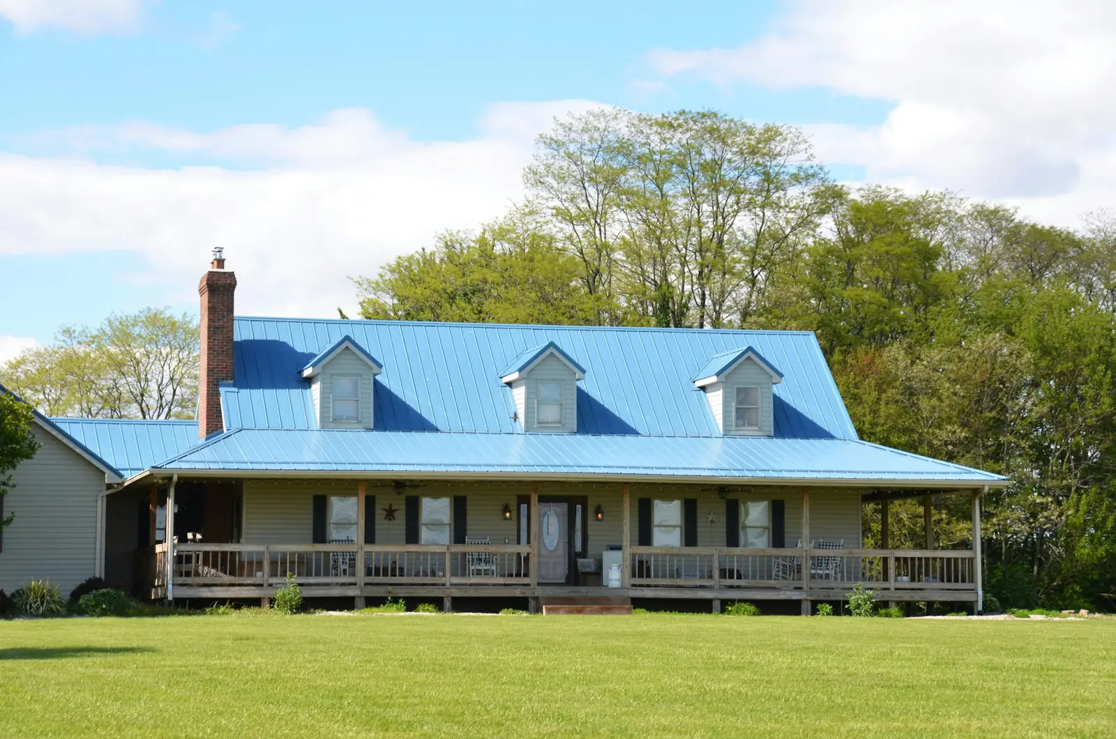 Farmhouse with an exposed-fastener ribbed metal roof and a long front porch