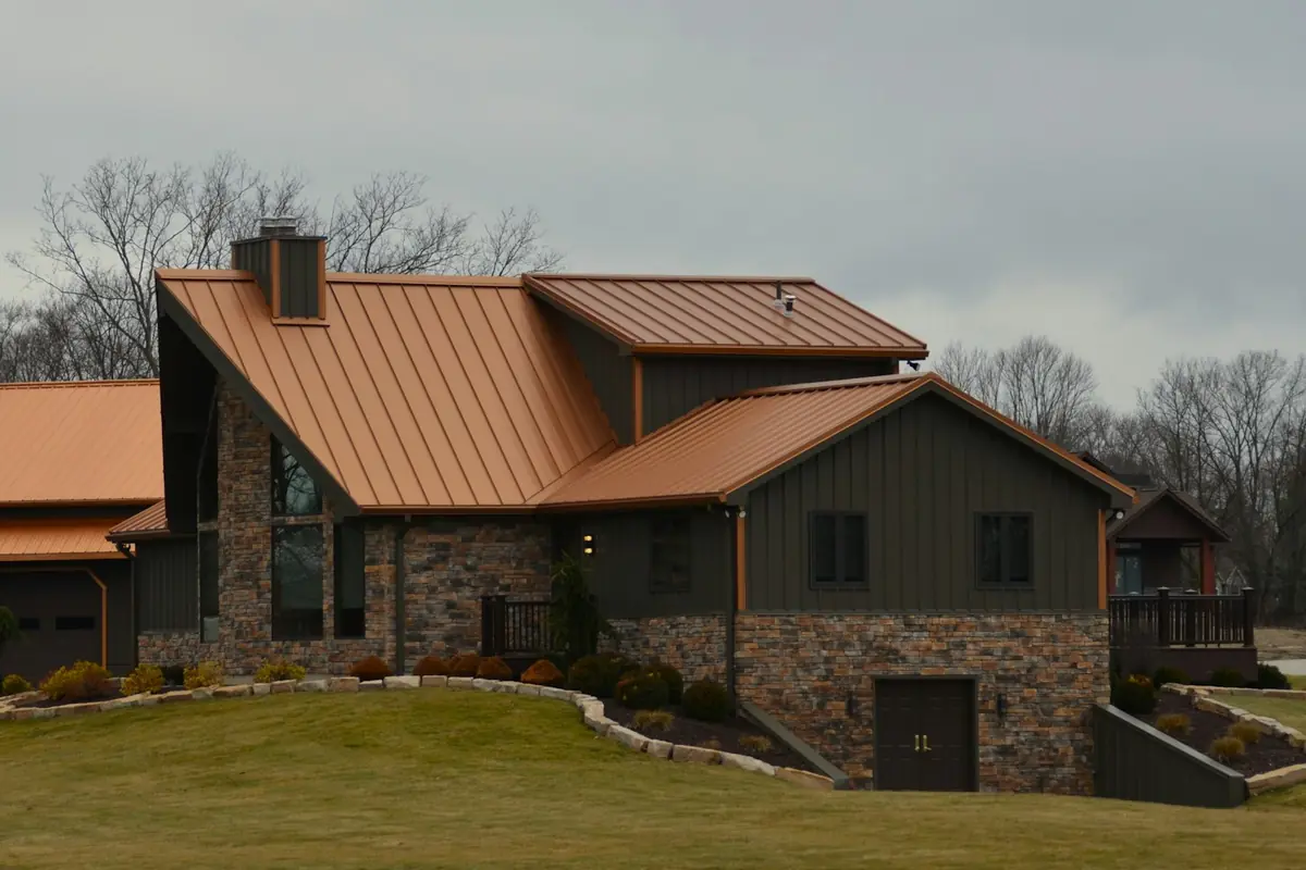 Copper-tone standing seam roof on a stone and board-and-batten house