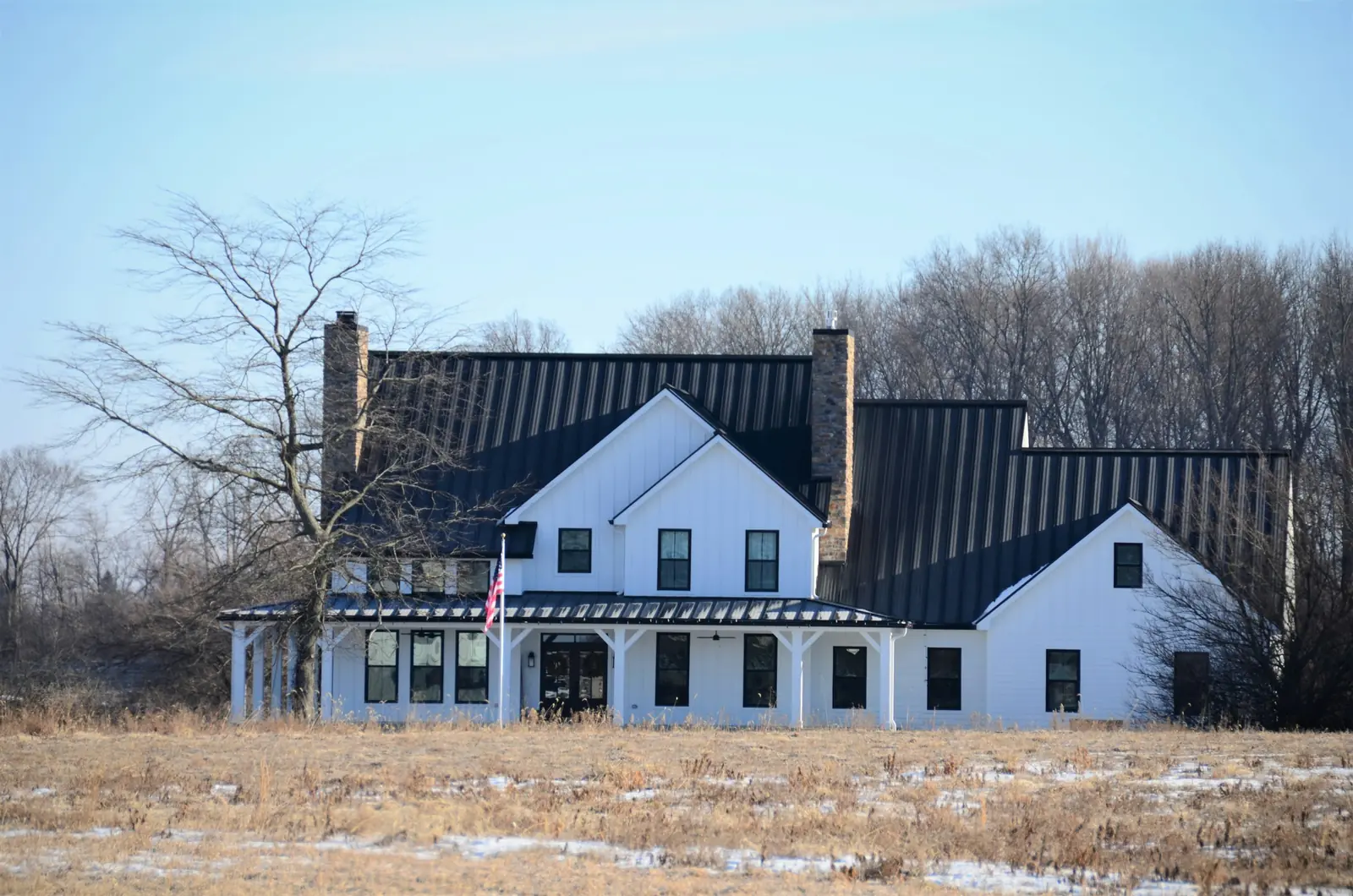 White farmhouse with a black standing seam metal roof