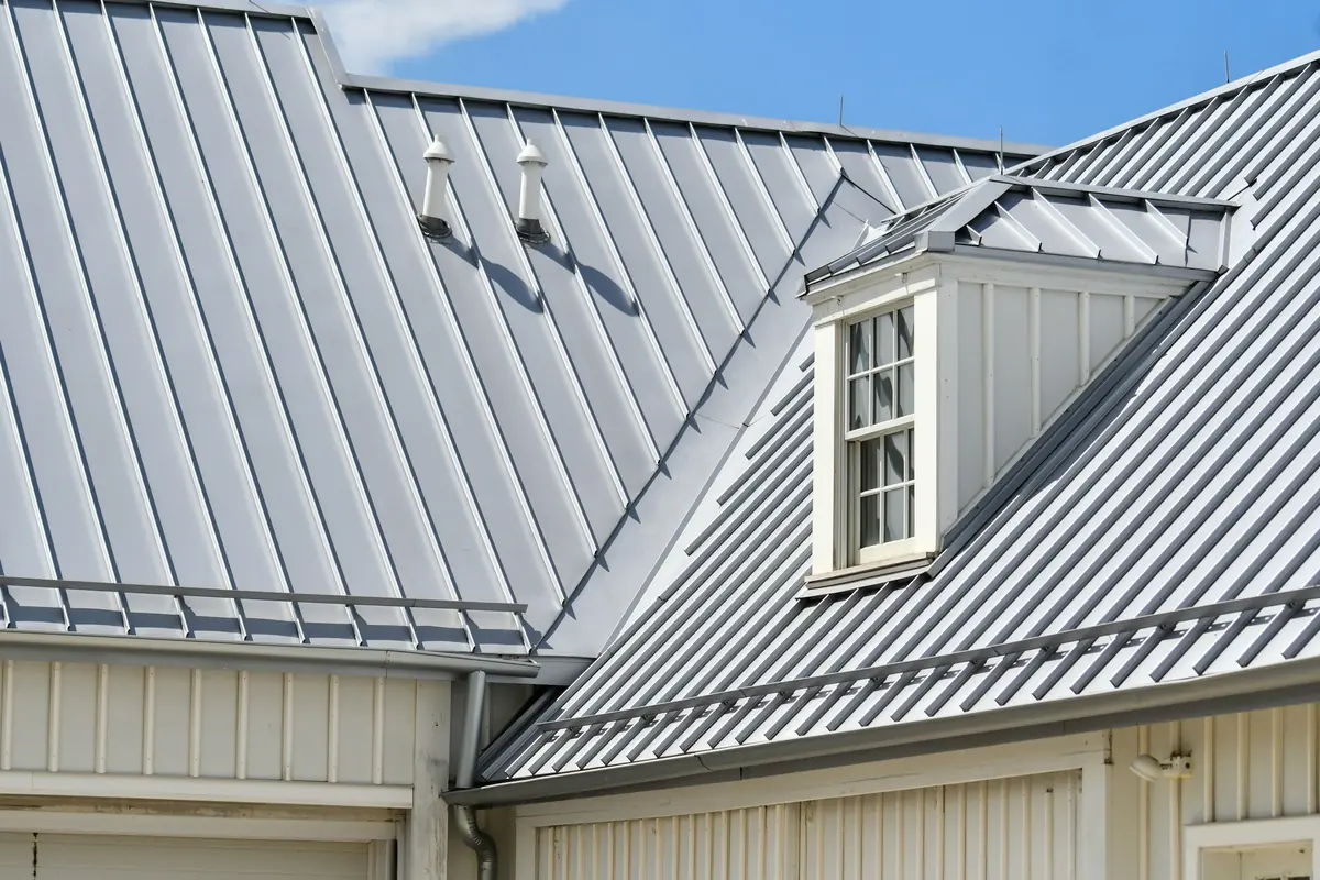 Gray standing seam roof with a dormer, a valley, and snow guards clamped across the seams
